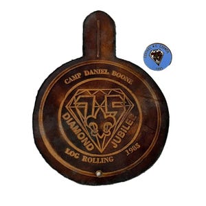 May include: A brown leather patch with the text "Camp Daniel Boone Diamond Jubilee 1985 Log Rolling" and a diamond shape with a scout emblem inside.