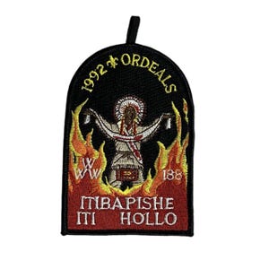 Puede incluir: Un parche bordado negro y rojo con una figura nativa americana en llamas. El texto dice "1992 * ORDEALS", "WW", "188", "ITIBAPISHE" y "ITI HOLLO".