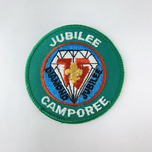 Może przedstawiać: Zielony haftowany znaczek z tekstem "Jubilee Diamond Jubilee Camporee" i diamentem z lilią w środku.