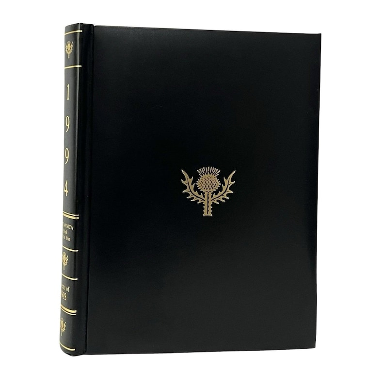 May include: A black hardcover book with gold lettering and a gold thistle emblem. The spine displays the year "1994" and the words "Britannica Book of the Year". The book is likely a reference or encyclopedia volume.