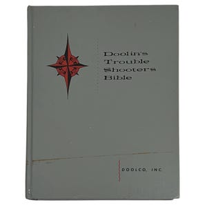 May include: A vintage book titled "Doolin's Trouble Shooters Bible" with a gray cover. The cover features a red and black compass rose design and the text in black. The publisher's name, DOOLCO, INC., is at the bottom.
