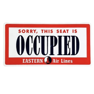 May include: A red and white sign with the text "Sorry, this seat is occupied" in black lettering. The sign also has the text "Eastern Air Lines" in black lettering with a red bird logo.