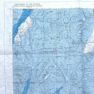 May include: A blue and white topographic map of the Fish Lake National Forest in Utah. The map shows the location of Fish Lake, Cove Mountain, and the Fish Lake Mountains. The map also includes elevation contours and other geographic features.