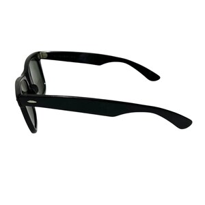 K&ouml;nnte beinhalten: Schwarze Sonnenbrille mit klassischem Rahmen. Die Sonnenbrille hat dunkle Gl&auml;ser und eine gl&auml;nzende Oberfl&auml;che. Die B&uuml;gel sind leicht gebogen, und die Gesamtform ist rechteckig. Seitenansicht.