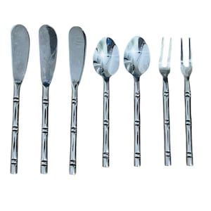 May include: A set of stainless steel silverware, including butter knives, spoons, and forks. The handles have a bamboo-like design. The silverware is arranged on a white background, reflecting light.