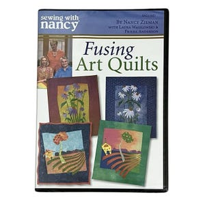 Puede incluir: Caja de DVD titulada "Fusing Art Quilts" de Nancy Zieman. La portada presenta una foto de tres personas y cuatro colchas artísticas con diseños florales y paisajísticos. La caja del DVD es negra.