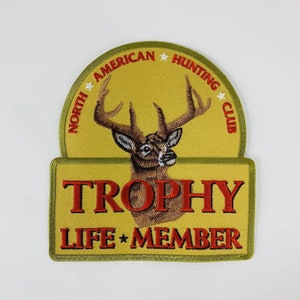 Könnte beinhalten: Ein gestickter Aufnäher in Gelb und Grün mit einem roten Hirschkopf und Geweih. Der Aufnäher trägt die Aufschrift "North American Hunting Club" und "Trophy Life Member".