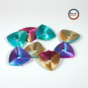 Das Foto zeigt mehrere dreieckige Fidget-Schlüsselanhänger mit sichtbaren ineinanderliegenden Ringen, in der Draufsicht. Beispielansicht zum digitalen STL-Modell.