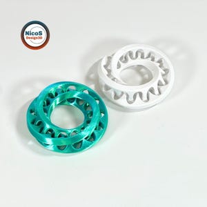Zu sehen: türkisfarbener und weißer Möbius-Ring-Fidget mit ineinandergreifenden Schlaufen. Beispielansicht zum digitalen STL-Modell.