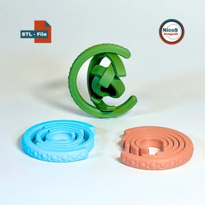 May include: Three 3D-printed objects in green, light blue, and peach. The green object is a complex knot shape. The light blue and peach objects are circular with a textured edge. The image includes the text "STL - File" and a logo for "Nicos Design3D".