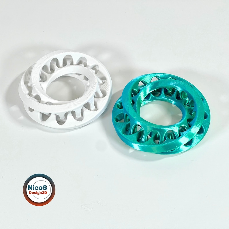 Zu sehen: drei Möbius-Ring-Fidgets in Türkis, Weiß und Beige, flach vor weißem Hintergrund. Beispielansicht zum digitalen STL-Modell.