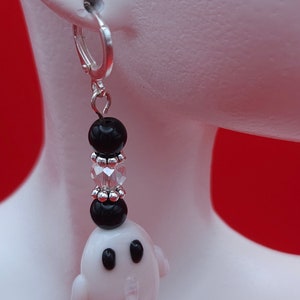 May include: Silver hoop earrings with black and clear beads and a white ghost charm.