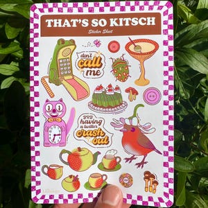 Op de afbeelding: Een stickerblad met een roze en bruine geruite rand. Het bevat kleurrijke illustraties, waaronder een kikkertelefoon, een kattenklok, een vogel en de tekst "THAT'S SO KITSCH".