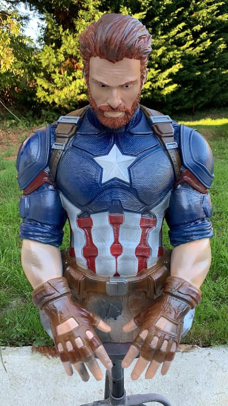 K&ouml;nnte beinhalten: Eine 3D-gedruckte B&uuml;ste von Captain America, der seinen ikonischen blau-roten Anzug mit einem wei&szlig;en Stern auf der Brust tr&auml;gt. Er hat einen braunen Bart und tr&auml;gt braune Lederhandschuhe.