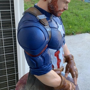 K&ouml;nnte beinhalten: Eine blaue und rote Captain America B&uuml;ste mit einem braunen Lederriemen und braunen Lederhandschuhen. Die B&uuml;ste ist aus bemaltem Kunststoff und eine Sammlerfigur.