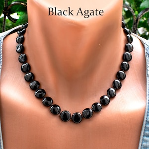 Puede incluir: Un collar de ágata negra pulida con cuentas redondas. El collar se muestra en un maniquí. El texto "Black Agate" se muestra encima del collar.