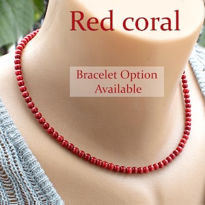 Op de afbeelding: Rode koraal ketting met kleine, ronde kralen. De ketting wordt getoond op een mannequin. De afbeelding bevat de tekst "Red coral" en "Bracelet Option Available".