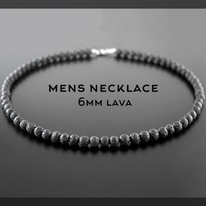 May include: A necklace composed of black, porous 6mm lava beads arranged in a circular pattern. The text MENS NECKLACE 6MM LAVA is centred within the loop of the beads. The beads have a rough, textured surface and are uniform in size.