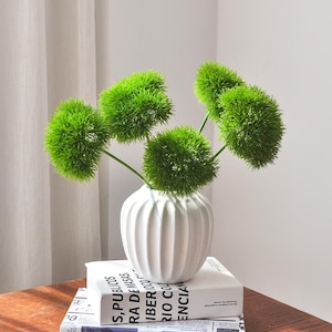 May include: A white ceramic mug with a black handle and the text "But First, Coffee" in a handwritten style. The mug is on a white surface. The mug is approximately 4 inches tall.