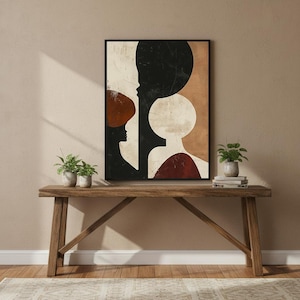 May include: Abstract art print with silhouettes and geometric shapes in black, white, and rust. The artwork is framed in a black border and displayed on a wooden console table with small potted plants.