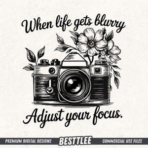 Puede incluir: Ilustración en blanco y negro de una cámara vintage con detalles florales. Incluye el texto: "When life gets blurry, adjust your focus."