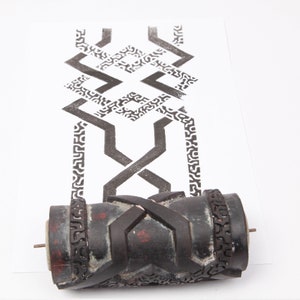 May include: A black and white patterned roller for creating decorative designs on surfaces. The roller is made of rubber and has a textured surface. The roller is shown next to a piece of paper with a sample of the design.