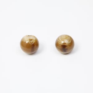 May include: Two spherical brown beads with a marbled, swirling design. The beads have a glossy finish and are set against a white background. These beads could be used for jewellery making or other craft projects.