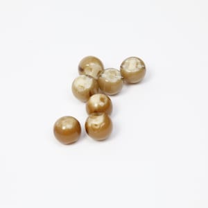 Könnte beinhalten: Acht runde, hellbraune Perlen mit glänzender Oberfläche liegen auf einer weißen Fläche. Die Perlen weisen eine glatte Textur und subtile Farbvariationen auf. Ideal für die Schmuckherstellung.