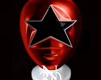 May include: A red plastic helmet with a black star in the center. The helmet is on a white stand with the letters "3D" printed on it.