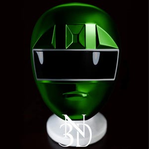 May include: A green plastic helmet with a black visor and a white stripe. The helmet is on a white stand.