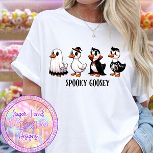 Pu&ograve; includere: T-shirt bianca con un design a tema Halloween. Il design presenta quattro oche dei cartoni animati in costume: un fantasma, una strega, un vampiro e uno scheletro. Il testo "SPOOKY GOOSEY" &egrave; incluso.