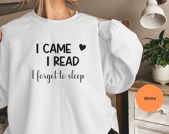May include: White sweatshirt with the text "I CAME, I READ, I forgot to sleep" in black. The sweatshirt has long sleeves and a crew neck. A small black heart is next to the word "CAME".