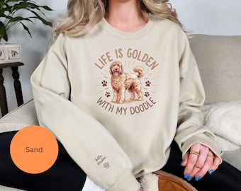 May include: Sand-colored sweatshirt with the text "LIFE IS GOLDEN WITH MY DOODLE" and a doodle dog graphic. The sweatshirt also features a paw print and the text "Bella Winston" on the sleeve.
