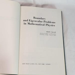 May include: Open book with the title "Boundary and Eigenvalue Problems in Mathematical Physics" on the right page. The author's name, Hans Sagan, and his affiliation are below the title. The publisher's name is at the bottom.