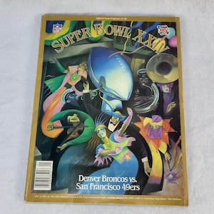 Könnte beinhalten: Ein offizielles Spielprogramm des Super Bowl XXIV im Vintage-Stil. Das Cover zeigt eine künstlerische Illustration mit Figuren, Musikinstrumenten und einem Football. Der Text lautet "Denver Broncos vs. San Francisco 49ers". Das Programm ist goldfarben umrahmt.