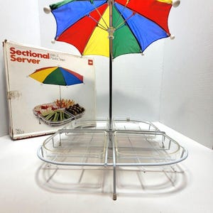 以下が含まれることがあります： 白い金属製のサービングトレイに、透明なプラスチック製のボウルが4つとカラフルな傘が置かれています。トレイには「Sectional Server」と「3103」の番号が書かれています。