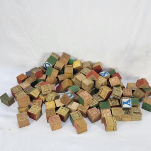 May include: A large collection of vintage wooden building blocks featuring various printed designs including brick patterns, windows, doors, and letters such as C, X, and Y. The blocks are square and triangular in shape with faded paint.