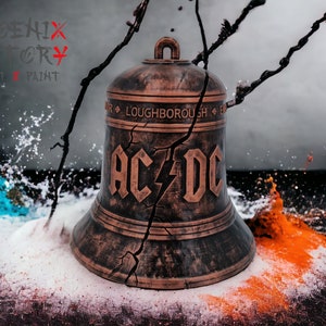 Peut inclure: Une cloche en bronze vieilli avec une surface fissurée et le logo AC/DC imprimé sur le devant. La cloche est entourée de poudre blanche et orange, et une branche avec des brindilles noires est en arrière-plan.
