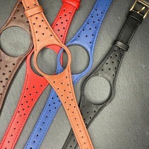 Könnte beinhalten: Eine Auswahl an farbigen Uhrenarmbändern in Braun-, Rot-, Blau- und Schwarztönen. Jedes Armband hat ein perforiertes Design und eine goldfarbene Schnalle. Die Armbänder sind aus Leder gefertigt und passen zu einem bestimmten Uhrenstil.