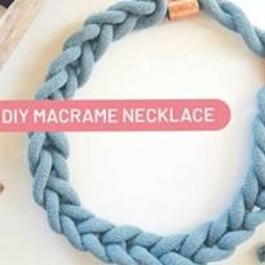 May include: A handmade macrame necklace in a light blue color. The thick, braided cord is accented with copper-colored metal clasps. The text "DIY MACRAME NECKLACE" is displayed on a pink banner.
