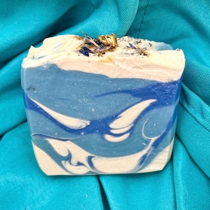 Jabón artesanal Coastal Rain, proceso en frío, hecho a mano en barra, con ingredientes naturales, aceite de argán, flores de jazmín y pétalos de aciano.