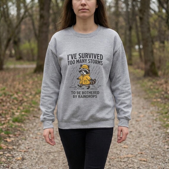 raccoon sweatshirt, motivational cozy crewneck, resilience quote, raincoat illustration, thoughtful gift, positive vibes, calm over chaos