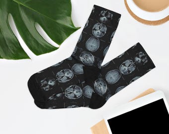 May include: Black socks with a repeating pattern of gray brain scan images. The socks are made of a soft material and are designed to fit most adult sizes. The socks are a unique and quirky accessory.