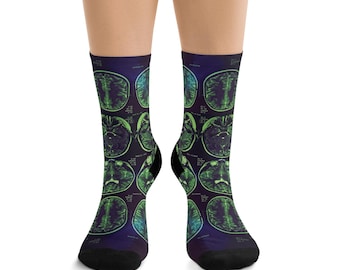 May include: A pair of crew socks featuring a dark purple background with a repeating pattern of green and black medical brain scan images. The socks have black toe and heel sections and include small white text labels near each scan.