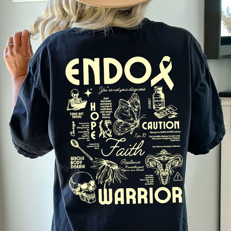K&ouml;nnte beinhalten: Schwarzes T-Shirt mit einem wei&szlig;en Grafikdesign, auf dem "Endo" steht und das einen Schmetterling, einen Sch&auml;del, eine Geb&auml;rmutter und die W&ouml;rter "Hope", "Faith", "Warrior" und "Caution: Allergic to Unsolicited Advice" enth&auml;lt.