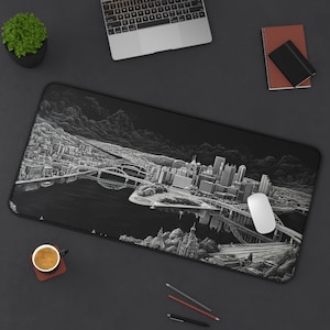May include: Black and white mousepad featuring a detailed cityscape design. The image shows bridges, buildings, and a river, with a laptop, mouse, and other office supplies on a dark surface.