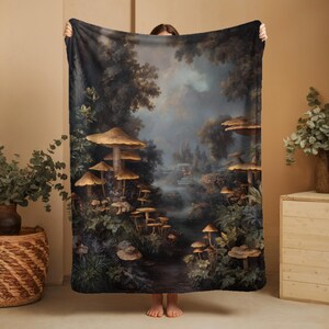 May include: A large, rectangular blanket featuring a detailed illustration of a forest scene with large mushrooms. The artwork has a vintage, painterly style with muted greens, browns, and blues. The blanket is held up, showcasing the full design.