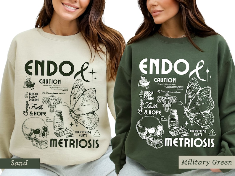 May include: Two sweatshirts with a graphic design featuring a butterfly, skull, and uterus. The text on the sweatshirts reads "Endo Caution" and "Metriosis". The sweatshirts are available in sand and military green.
