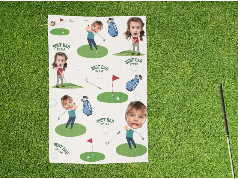 May include: Golf towel with a repeating pattern of cartoon figures playing golf, golf bags, golf balls, and flags on green patches. The text "BEST DAD BY PAR" is repeated throughout the design. The towel has a loop for hanging.