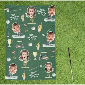 May include: Green golf towel with a repeating pattern of cartoon golfers, golf balls, golf carts, and trophies. The towel has the text "BEST GRANDPA BY PAR" and includes a loop for hanging.